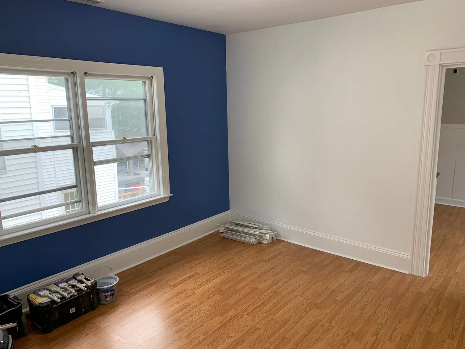 A bedroom with one deep navy accent wall meeting crisp white walls and window trim