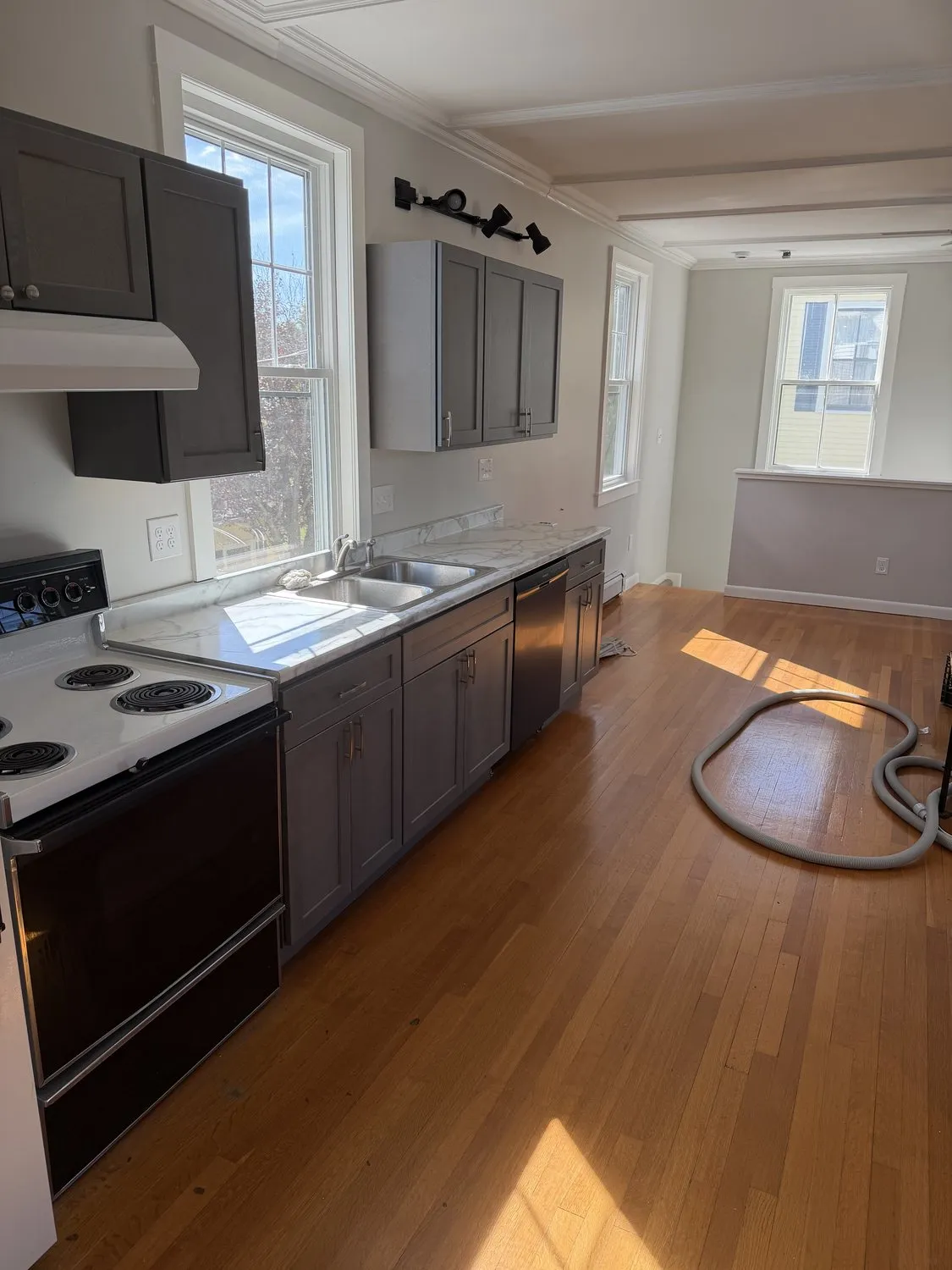 A finished Danvers kitchen with gray cabinets, white walls and a hardwood floor