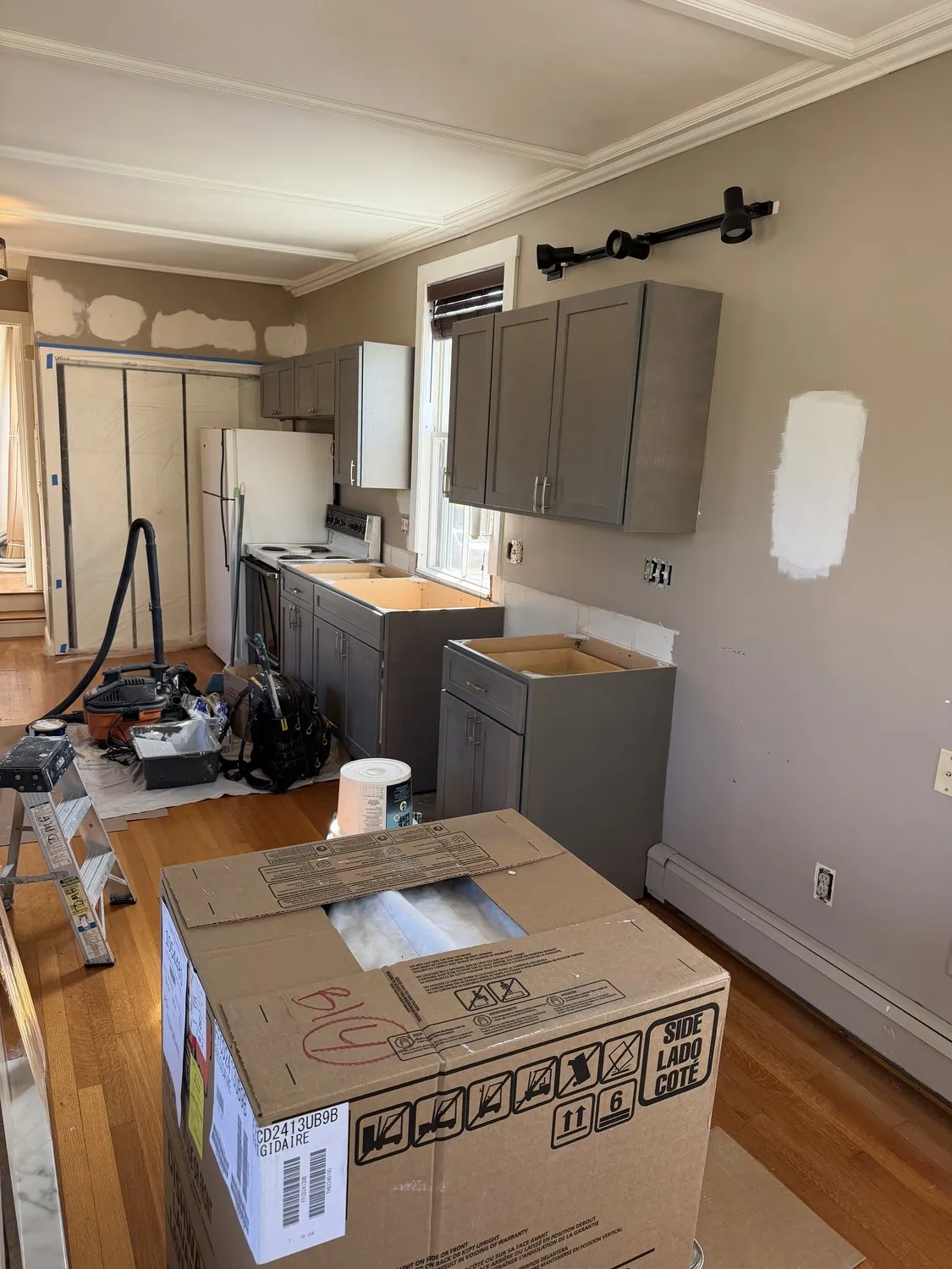 A Danvers kitchen part-way through the work, with cabinets masked and floors covered