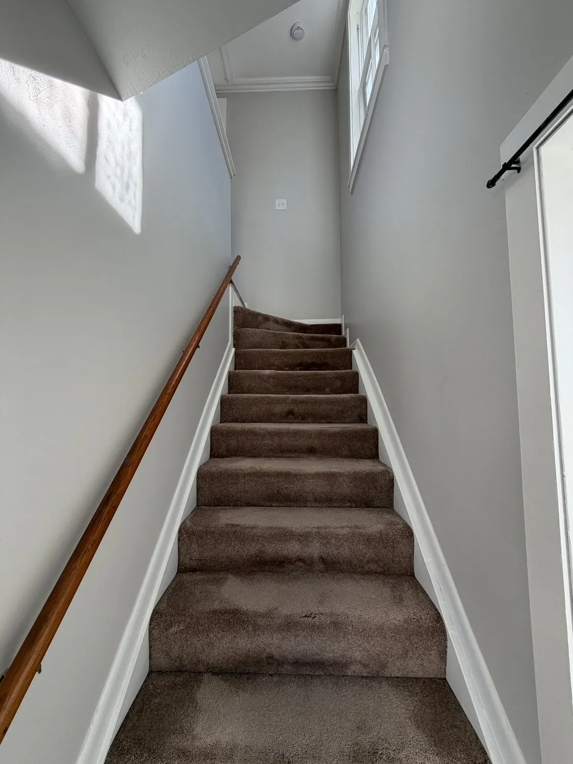 A Danvers stairway with freshly painted white walls and a wood handrail