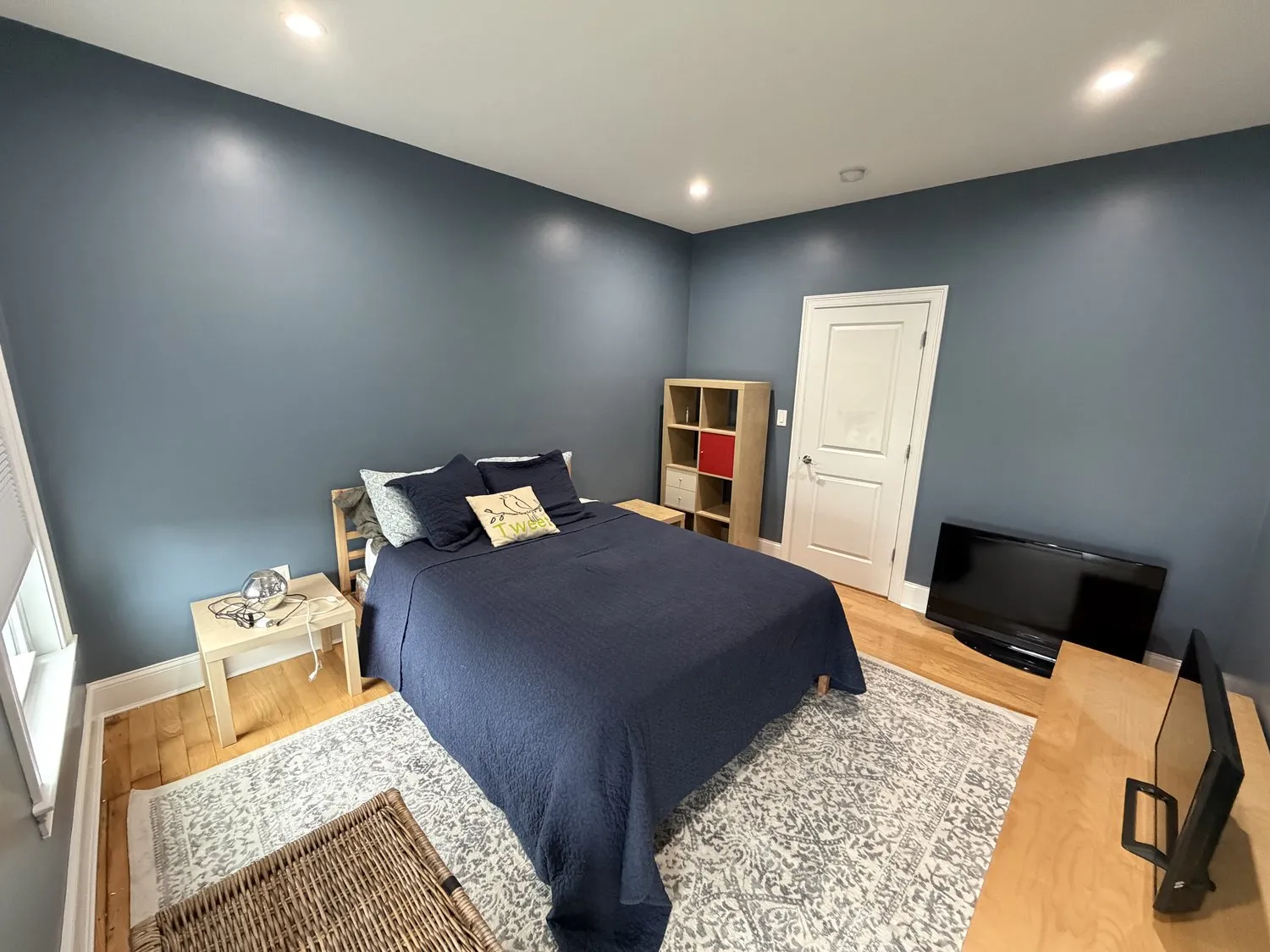 A wide view of a navy Dorchester bedroom with three windows and white casings