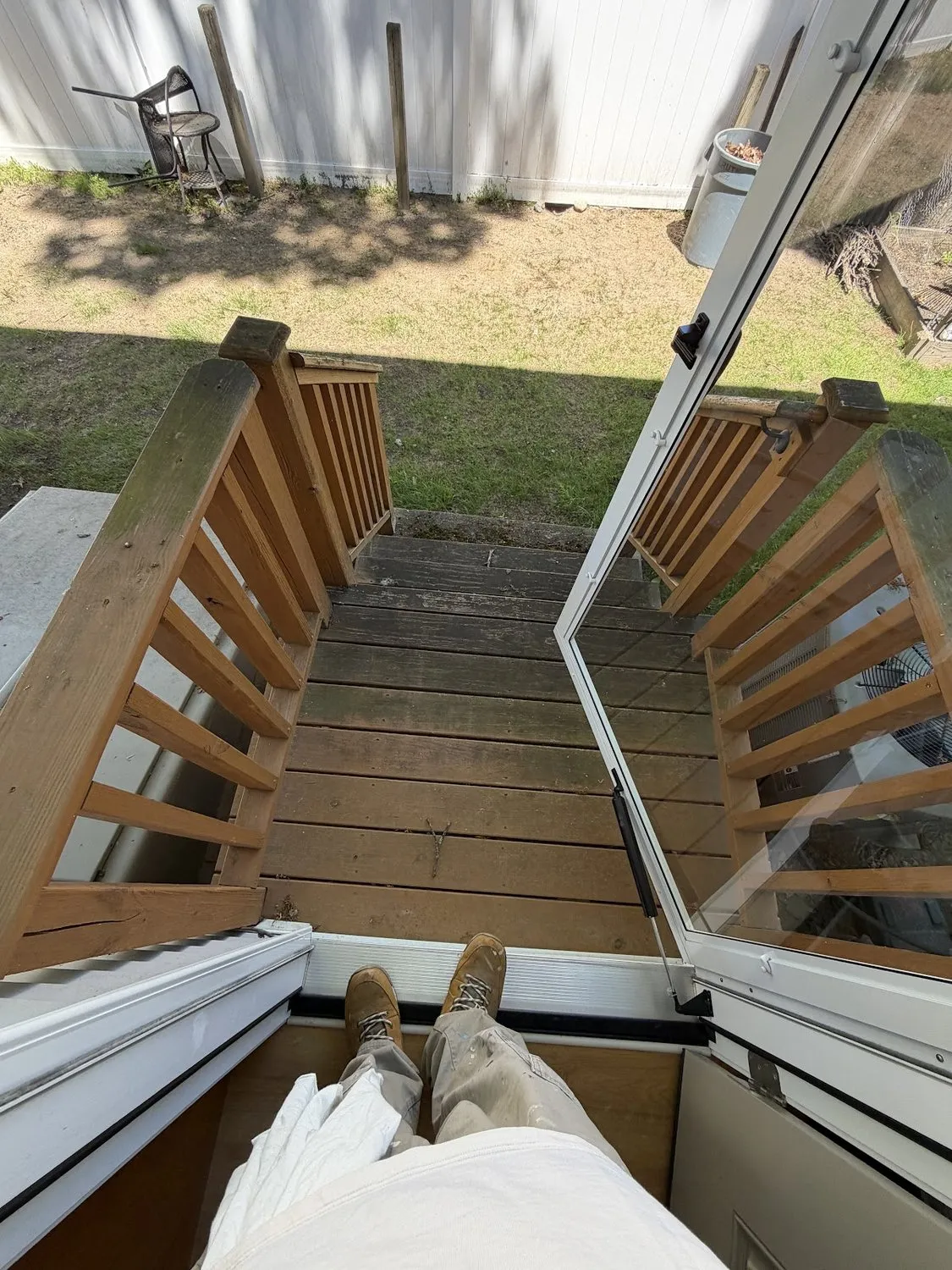 Wood deck stairs and railings photographed from above, leading down to a lawn