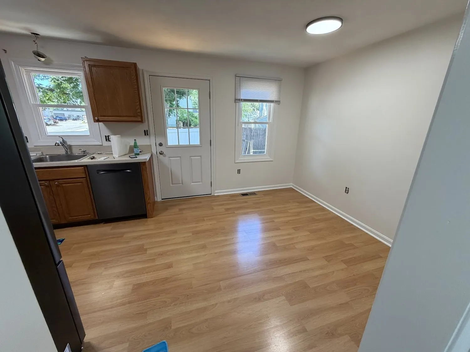An empty kitchen and dining space with soft gray walls and a wood floor