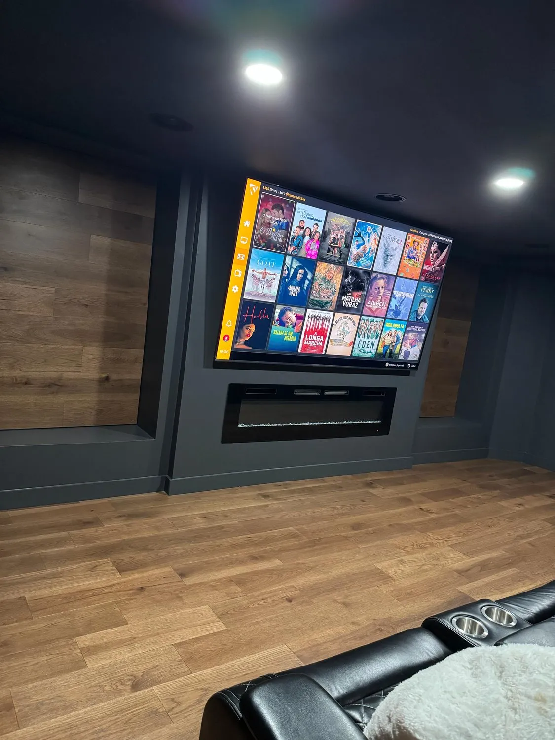 A Leominster cinema room with a linear fireplace below the screen and wood paneling