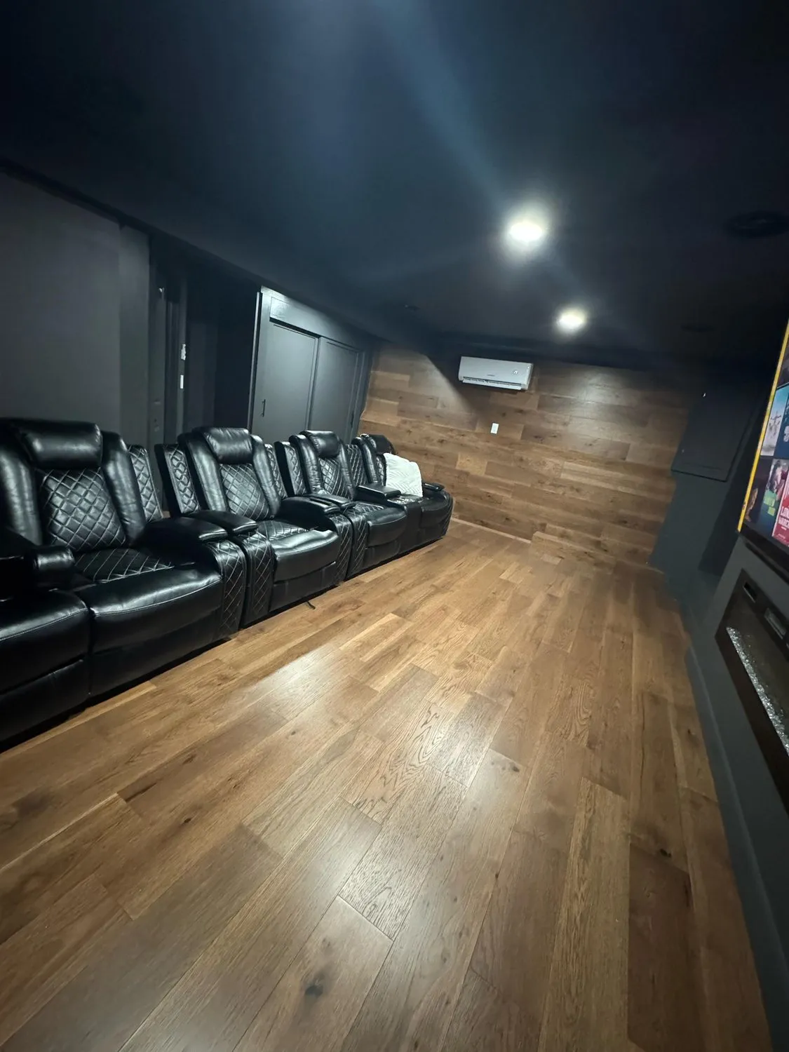 Tiered leather seating in a Leominster home cinema with dark walls and a wood floor