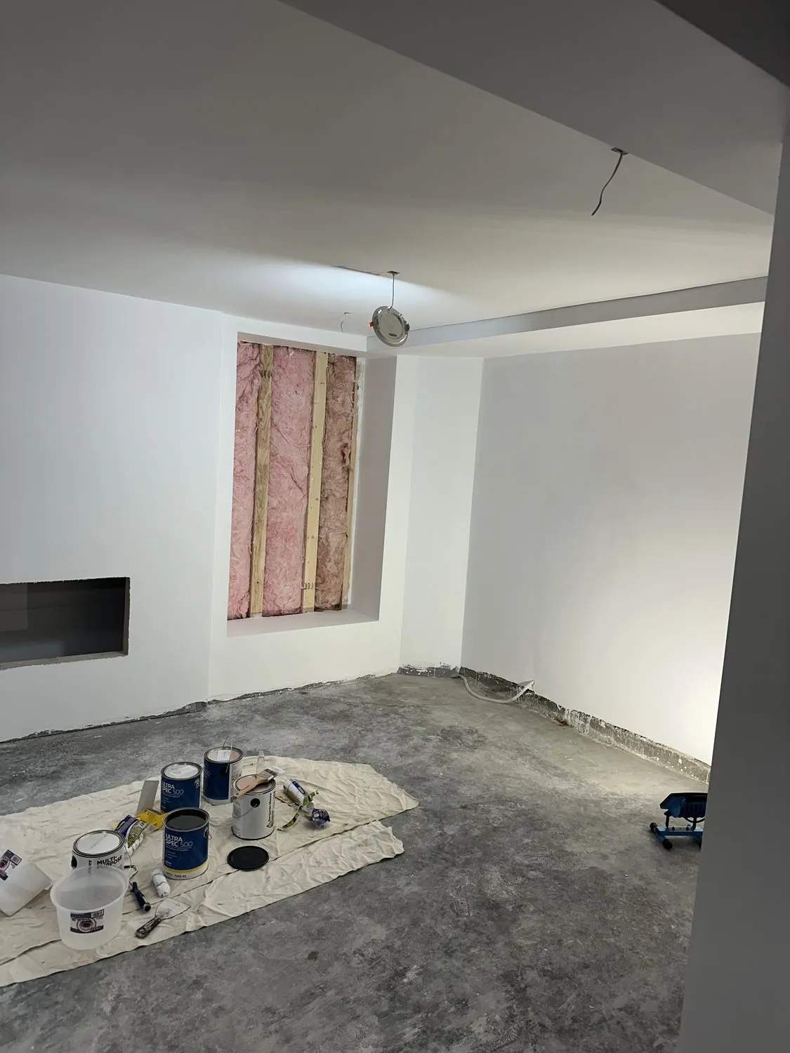 A Leominster room primed white with a bare concrete floor and materials laid out