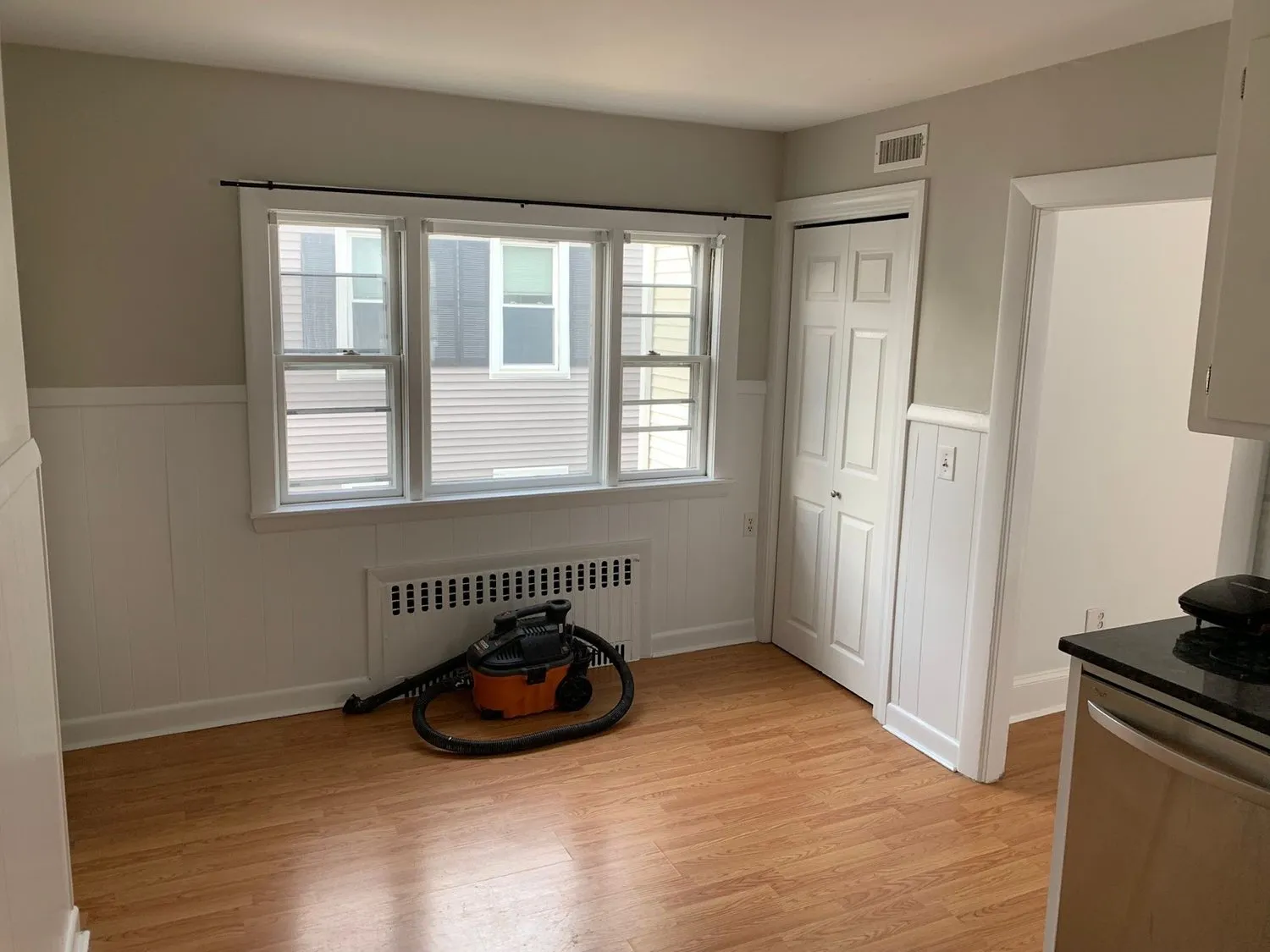 An empty living room painted in two tones, gray above white wainscot paneling
