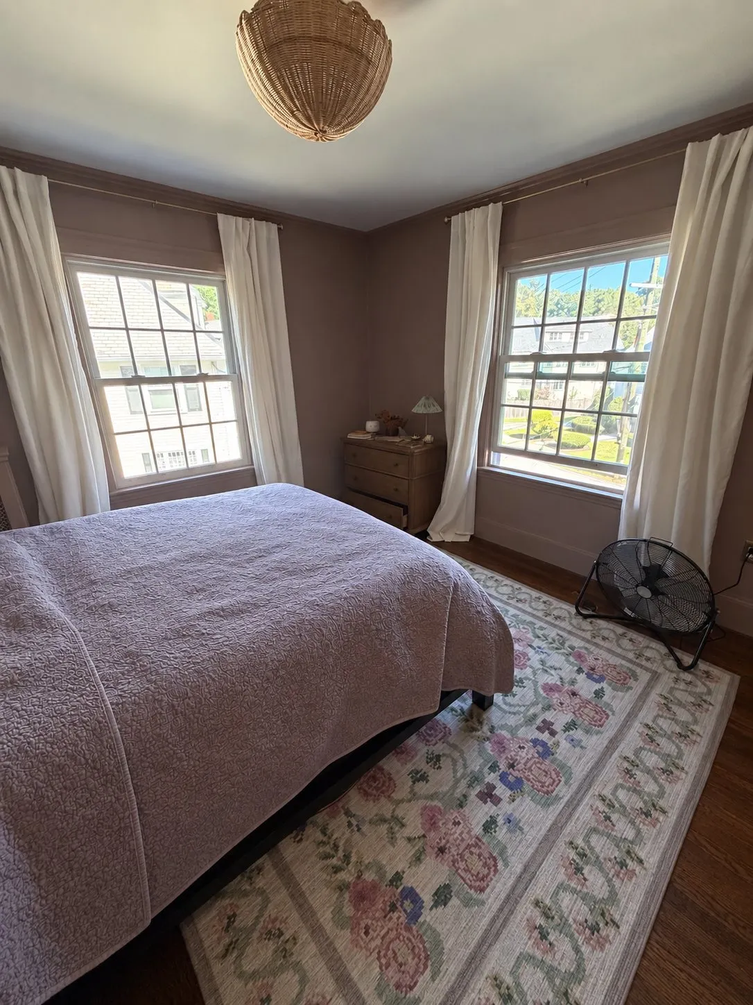 A Newton bedroom painted dusty rose with white window trim and a patterned rug