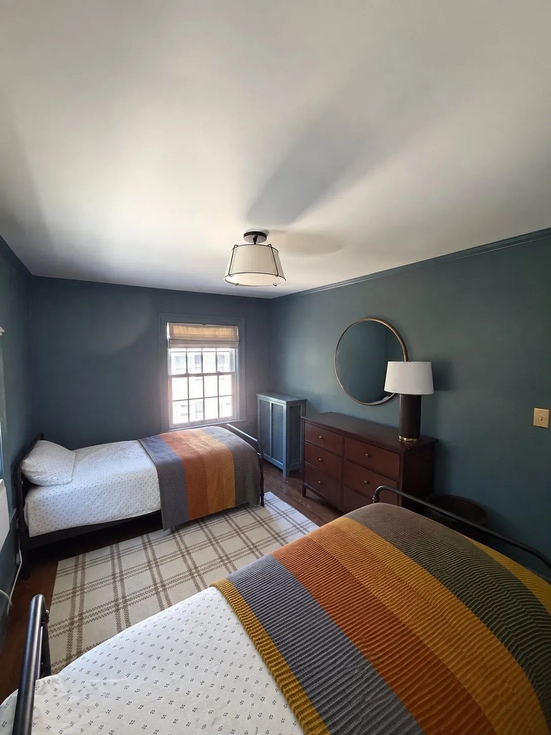 A Newton bedroom with deep teal walls, white ceiling and twin beds