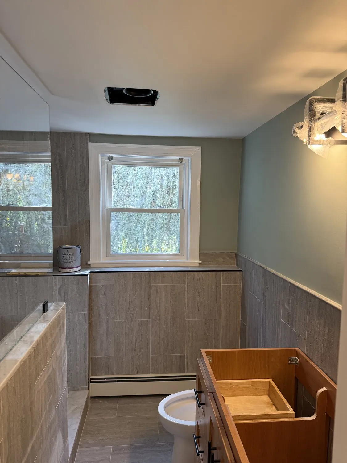 A Norwood bathroom in soft sage with wood-look wainscot and a window