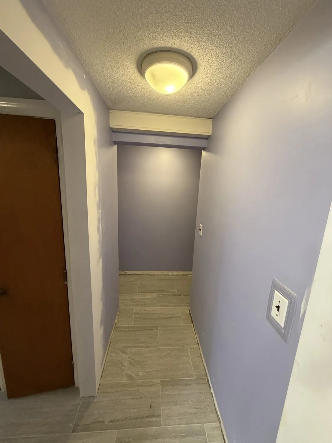 A Norwood hallway in lilac with a wood door and tiled floor