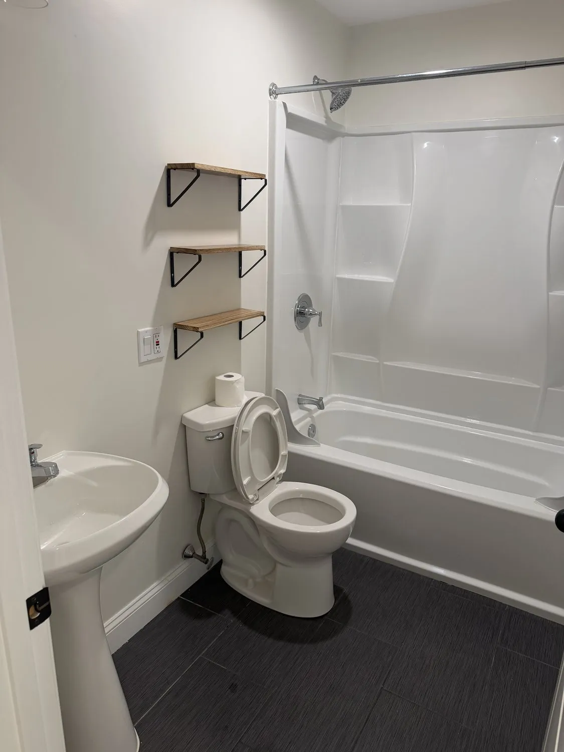 A Roxbury bathroom painted white with a dark tiled floor and open shelving
