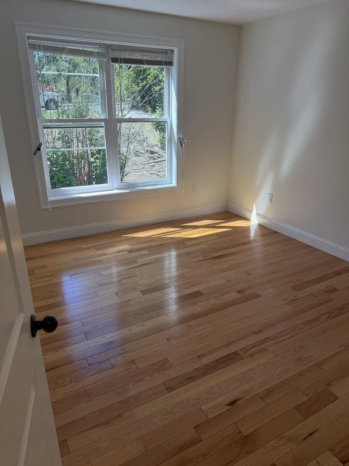 An empty Roxbury bedroom painted white with a refinished hardwood floor