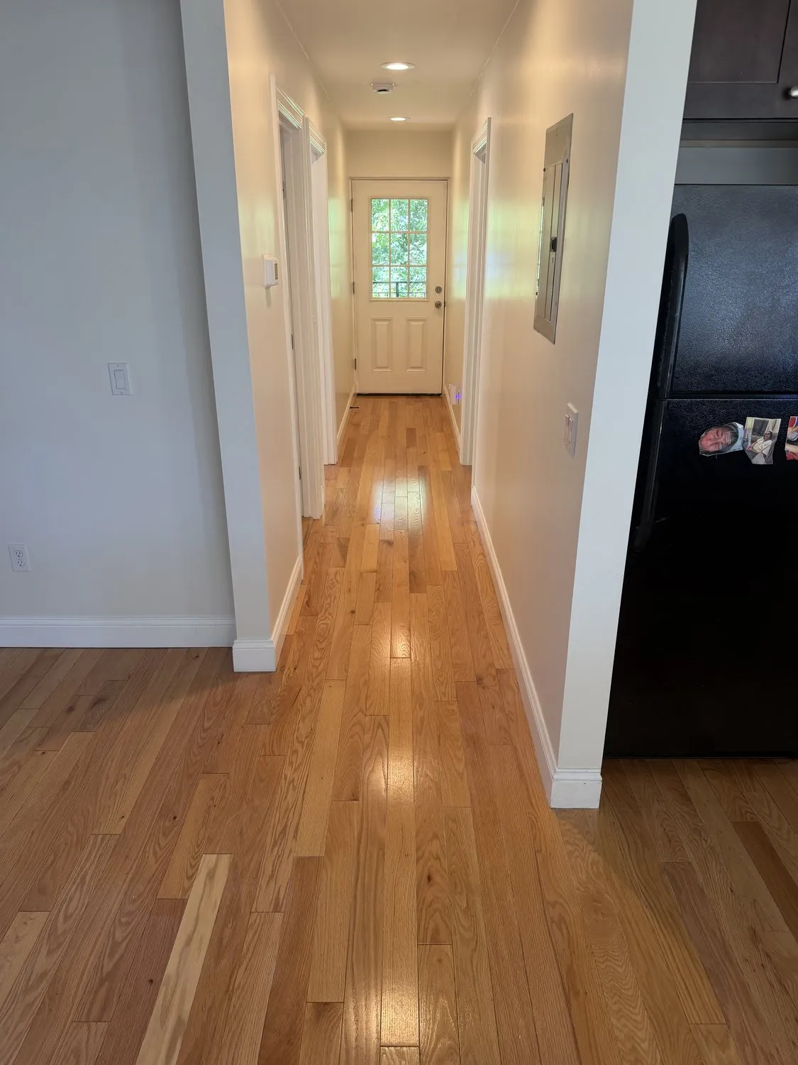 A Roxbury hallway painted white, running through to a front door with light on the floorboards